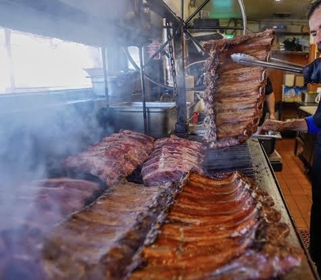 Ribs and carne grilling over an open mesquite flame at Tacos Apson